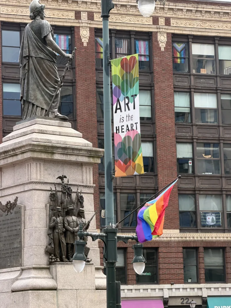 Tried & True medical cannabis delivery vehicle route past Monument Square and the Arts District flags during Pride in Portland Maine.